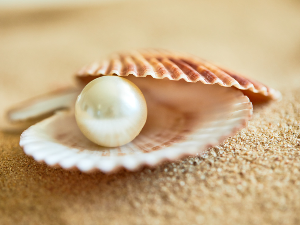 a pearl stone placed on sand 